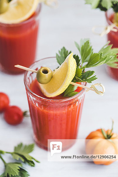 Glasses of fresh spicy tomato juice with cellery garnished with lemon slice  green olive and parsley