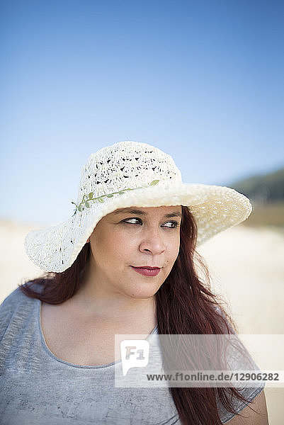 Portrait of woman wearing summer hat on the beach watching something