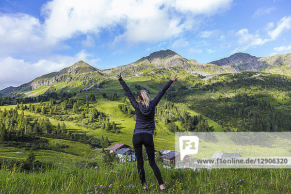 Austria  Salzburg State  Obertauern  woman standing on viewpoint  raised arms  rear view