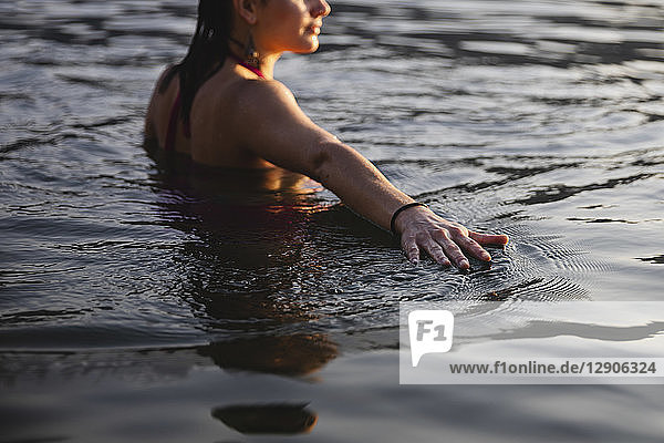 Hand of young woman touching the water surface in a lake