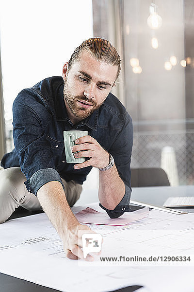 Young businessman working on plan at desk in office