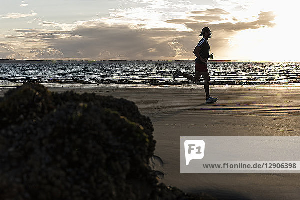 Jogger running on he beach at sunset