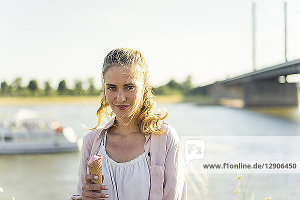Portrait of smiling woman eating ice cream in summer at the riverside