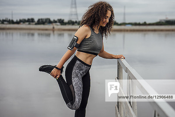 Young athletic woman stretching at the riverside