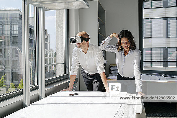 Two architects working on blueprints  man using VR glasses