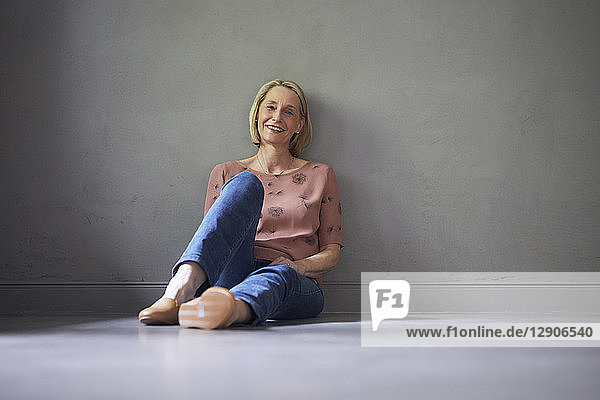 Portait of smiling mature woman at home sitting on the floor