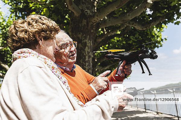 Senior couple playing with a drone in park