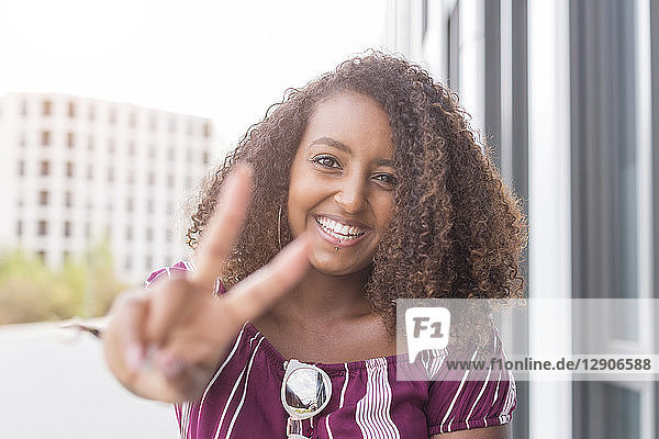Portrait of smiling young woman showing victory sign