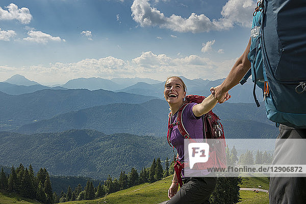 Germany  Bavaria  Brauneck near Lenggries  happy young woman hiking in alpine landscape holding hand of boyfriend