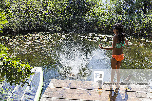 Girl watching her friend jumping into pond