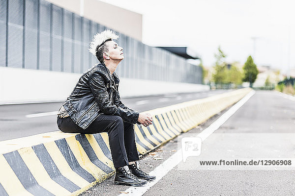 Punk woman sitting at the roadside with closed eyes