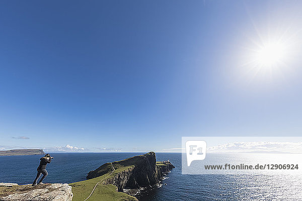UK  Scotland  Inner Hebrides  Isle of Skye  tourist taking picture of lighthouse at Neist Point
