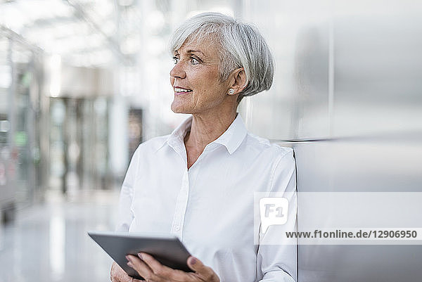 Portrait of smiling senior businesswoman holding tablet