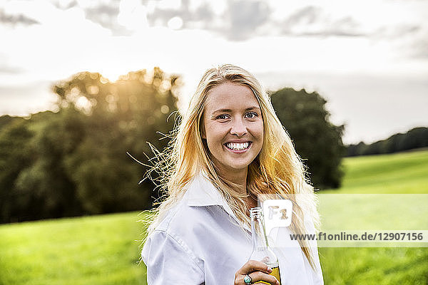 Portait of happy woman drinking beer in rural landscape