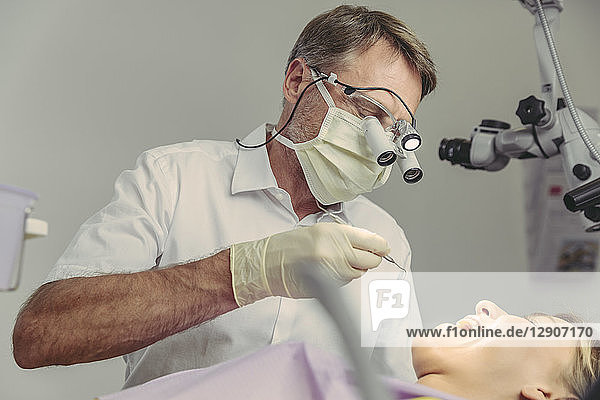 Dentist examining his patient  using dental microscope