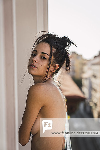 Portrait of beautiful barechested young woman on balcony above the city