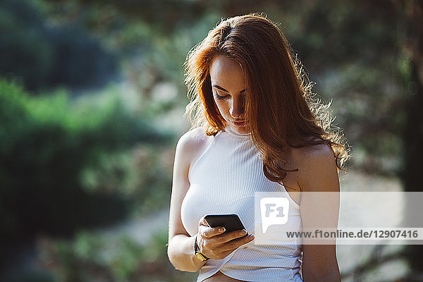 Redheaded woman using cell phone outdoors