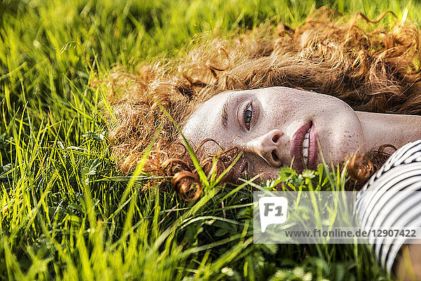 Portrait of redheaded young woman lying on meadow