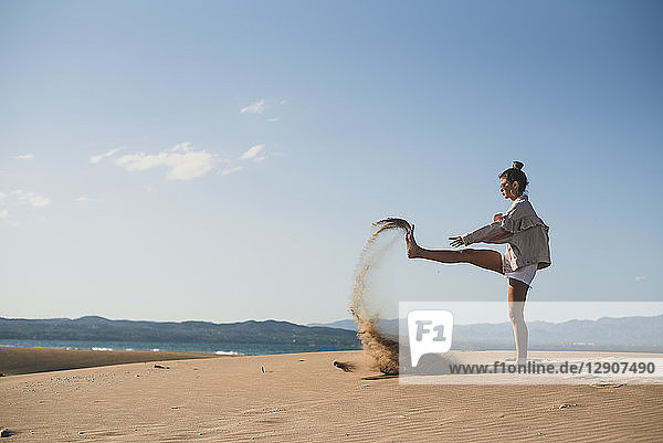 Teenage girl throwing sand on the beach