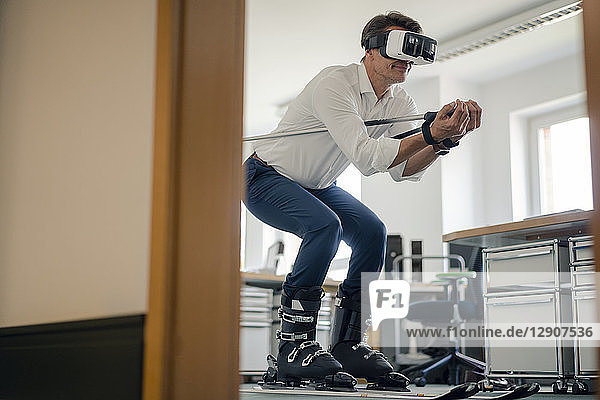 Businessman skiing in office  using VR glasses