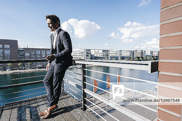 Businessman standing on balcony  holding smartphone