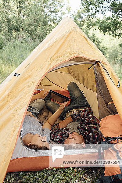 Young couple relaxing in tent  using digital tablet
