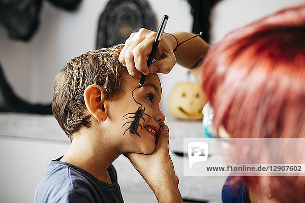 Mother painting her son's face for Halloween