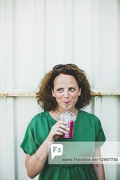 Portrait of smiling woman drinking fruit smoothie outdoors
