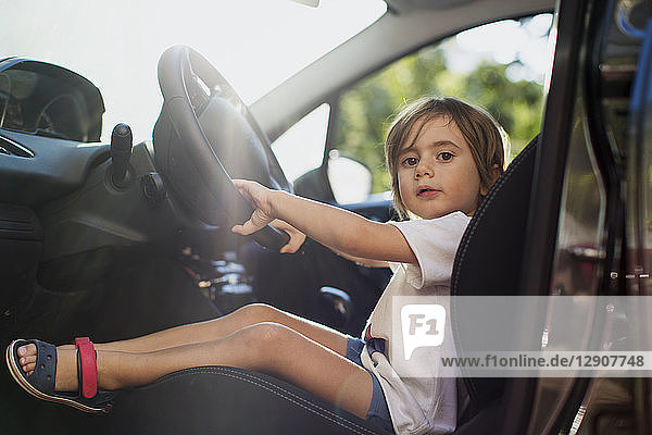 Portrait of little boy sitting on driver's seat in a car