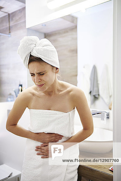 Young woman in bathroom suffering from stomach pain