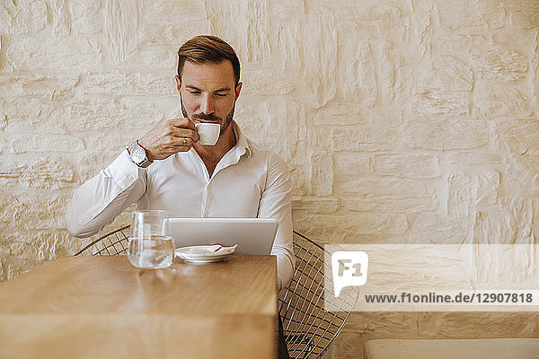 Man with tablet drinking espresso in a cafe