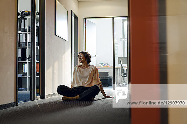 Businesswoman sitting cross-legged on floor in office