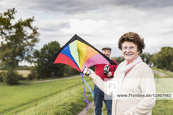 Portrait of smiling senior couple with kite in rural landscape