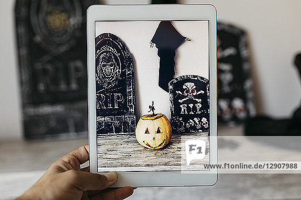 Man taking photo of Halloween decoration with digital tablet