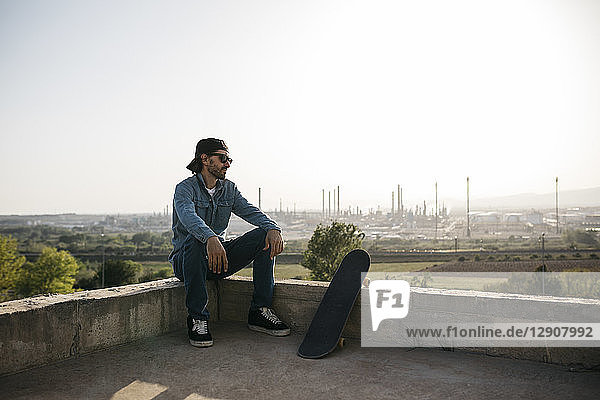 Skateboarder dressed in casual clothes resting at sunset