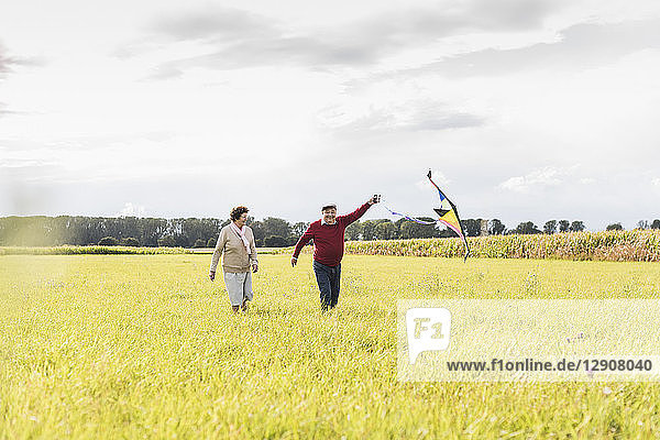 Happy senior couple flying kite in rural landscape