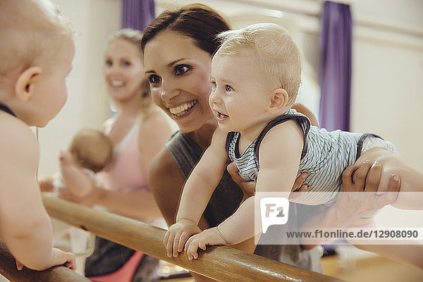 Mother holding up her baby to barre in dance studio