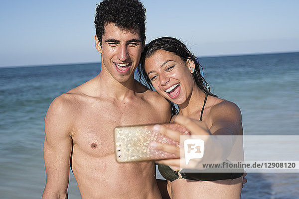 Happy young couple taking selfies on the beach