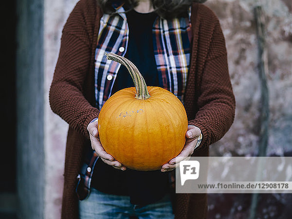 Woman's hands holding big pumpkin
