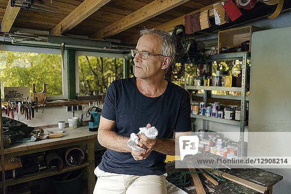 Mature man in his workshop cleaning his hands