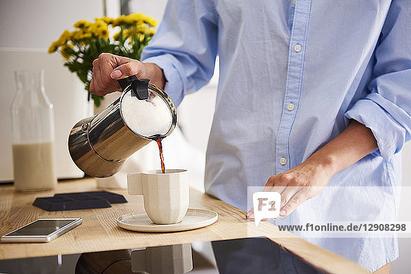 Young woman pouring coffee in cup