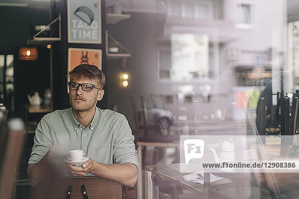 Young business owner sitting in his coffee shop  drinking coffee