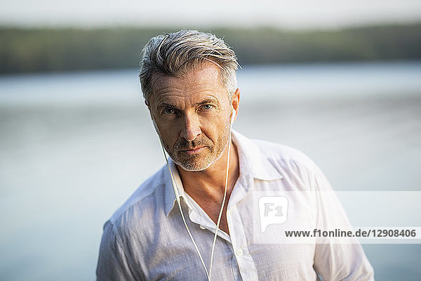 Portrait of mature man with earphones at lake