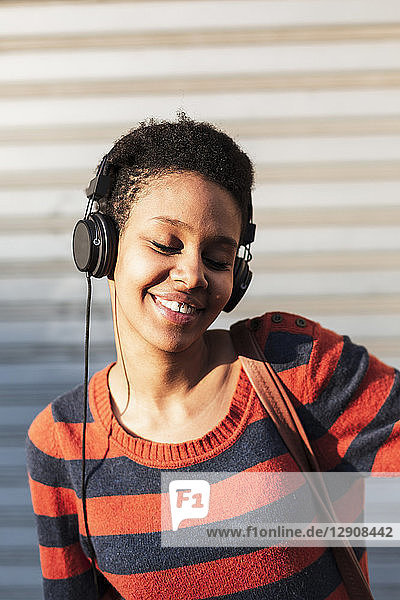 Portrait of smiling young woman listening music with headphones