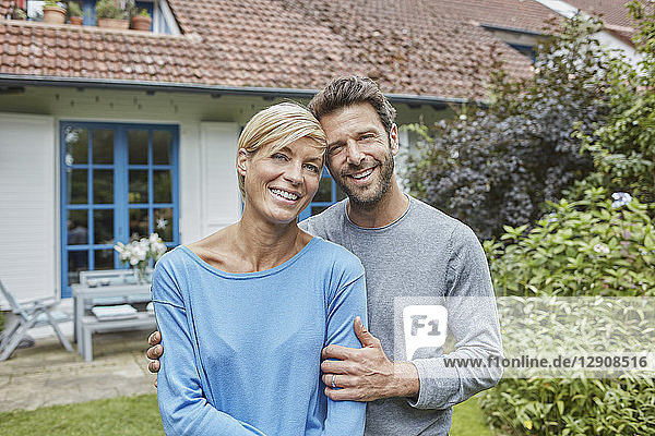 Portrait of smiling couple standing in front of their home