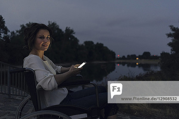 Disabled woman sitting in wheelchair  using smartphone