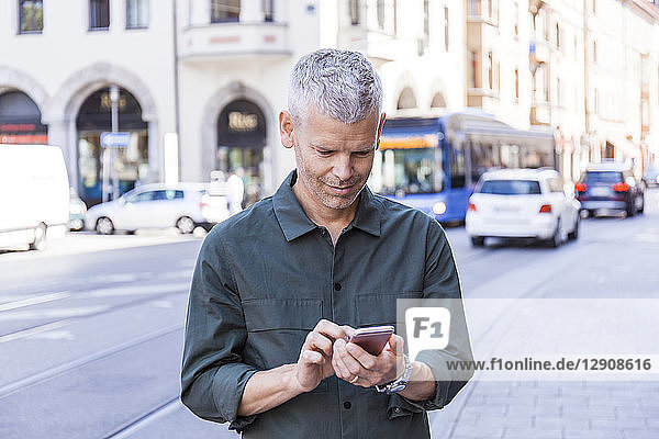 Mature man using cell phone in the city