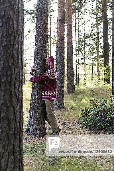 Finland  Young man hugging trees in a forest
