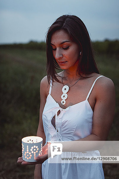 Young woman in nature  holding candle in the evening