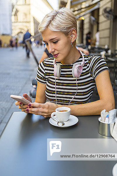 Italy  Florence  portrait of young woman at pavement cafe looking at smartphone